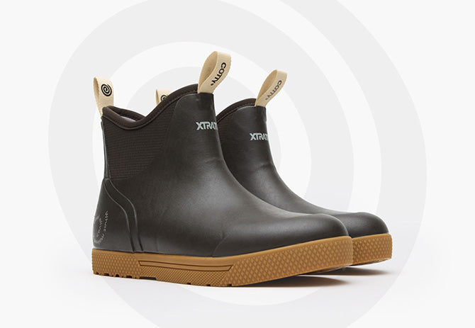 Pair of black rain boots with brown soles on a white background