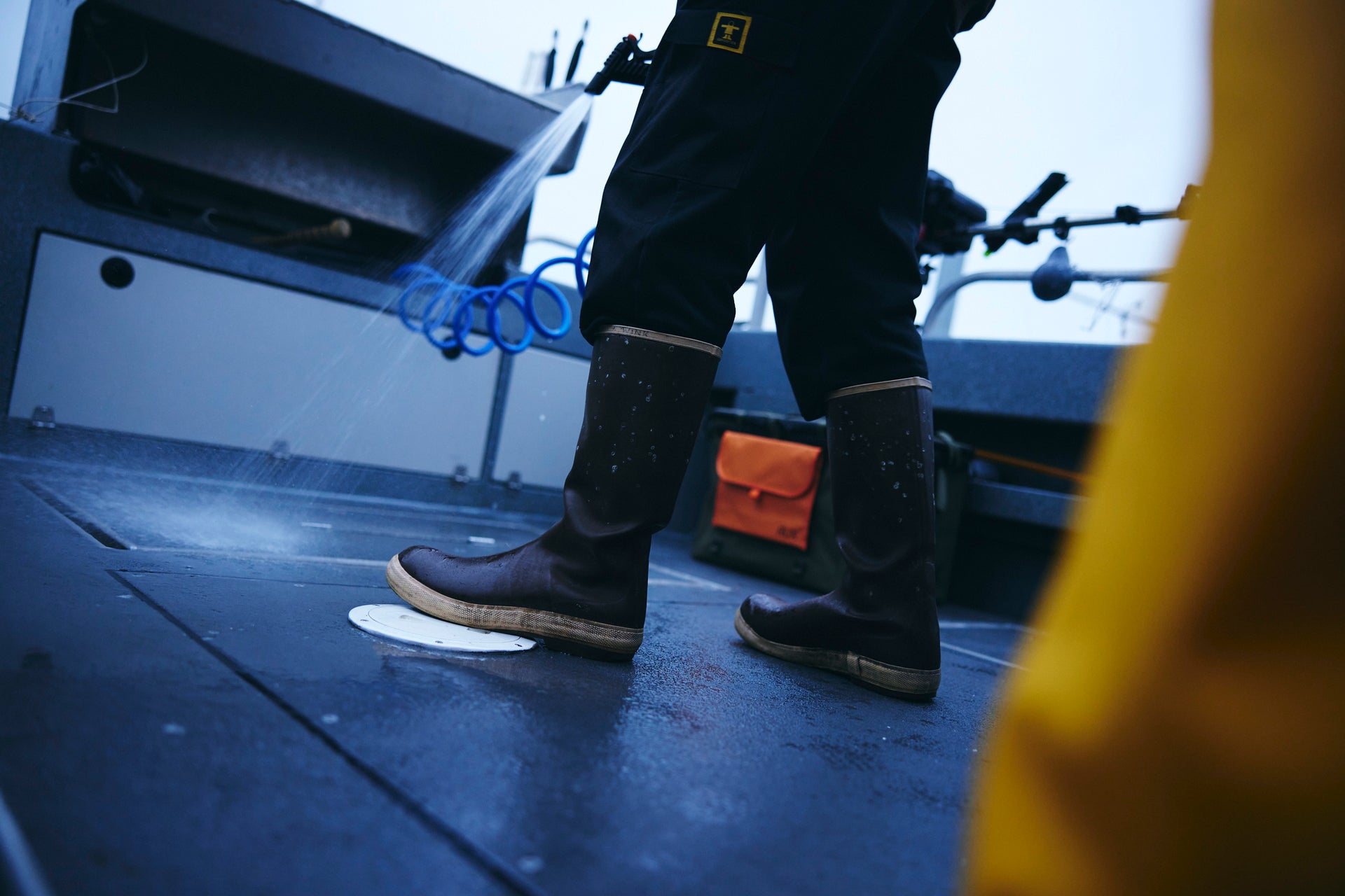 Person wearing rubber boots on a boat deck with a blurred background