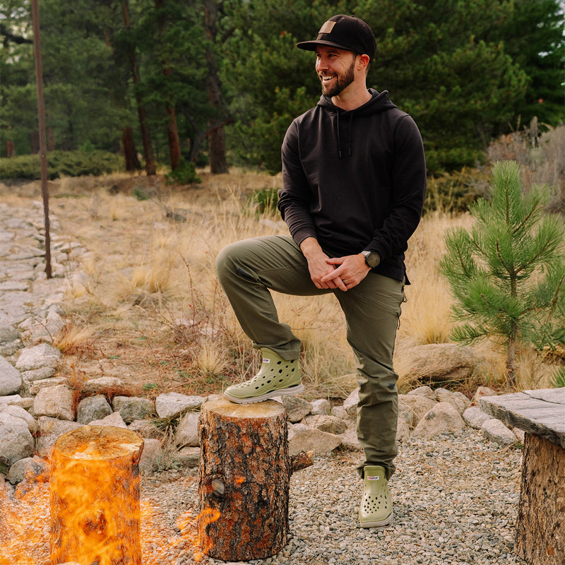 Man sitting on a log by a campfire in a forest setting