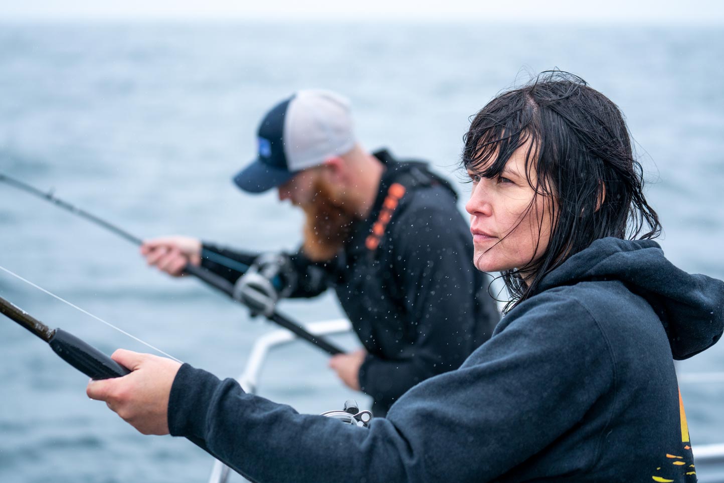 Two people fishing on a boat with a blurred water background
