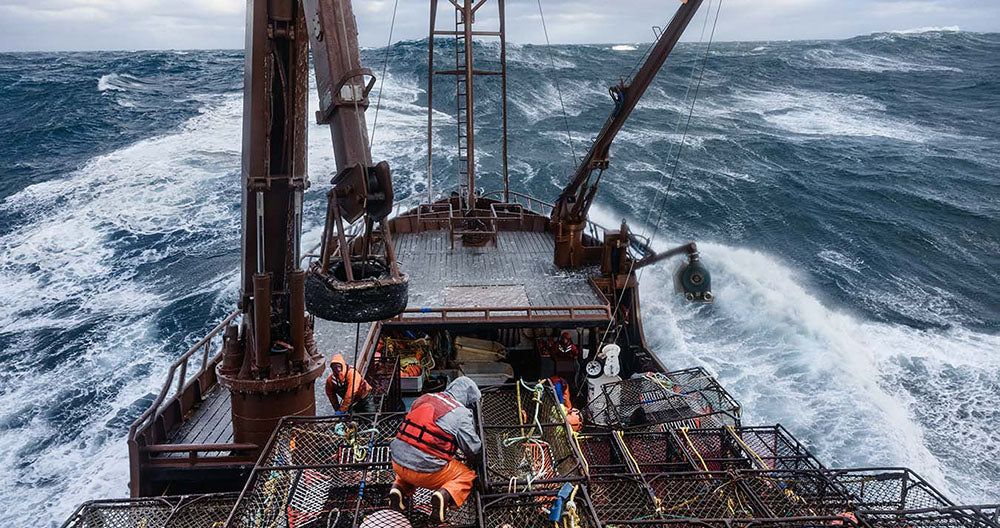 Fishing boat navigating rough seas with equipment on deck