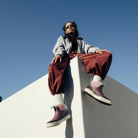 Person sitting on a white wall with a clear blue sky background