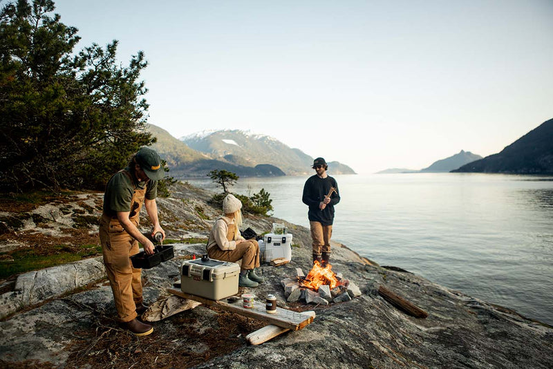 A team of 2 men and 1 women camping on bank of lake