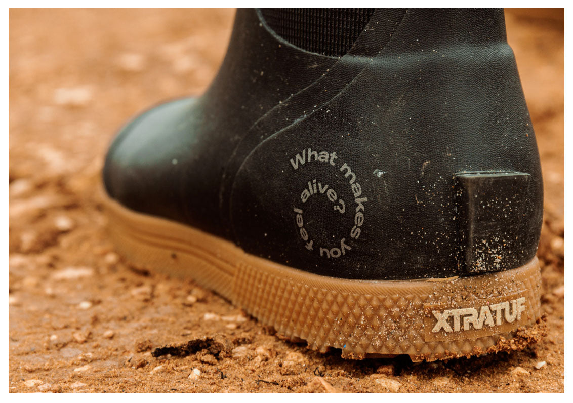 Black rubber boot with text on a brown ground