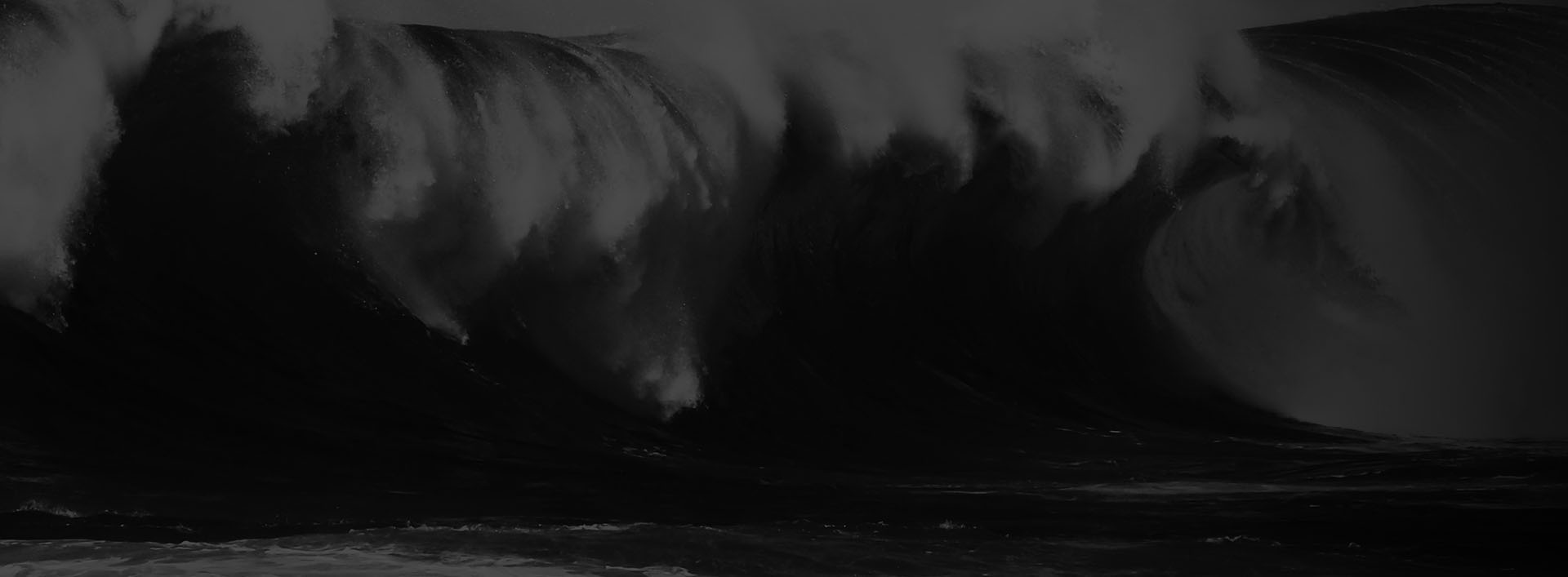 Black and white photo of a person lying on a beach with waves crashing around