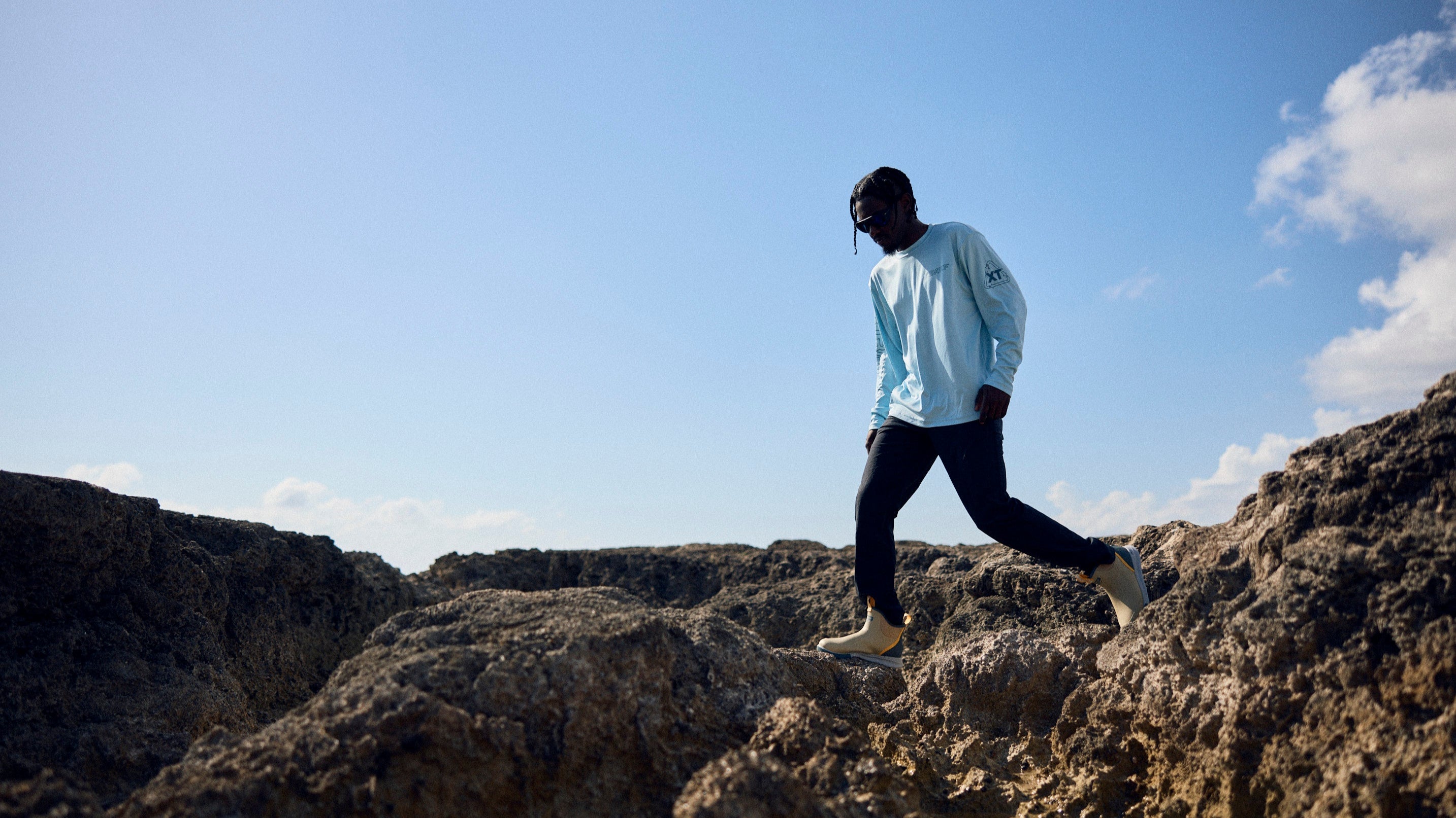 Person walking on rocky terrain with a clear blue sky