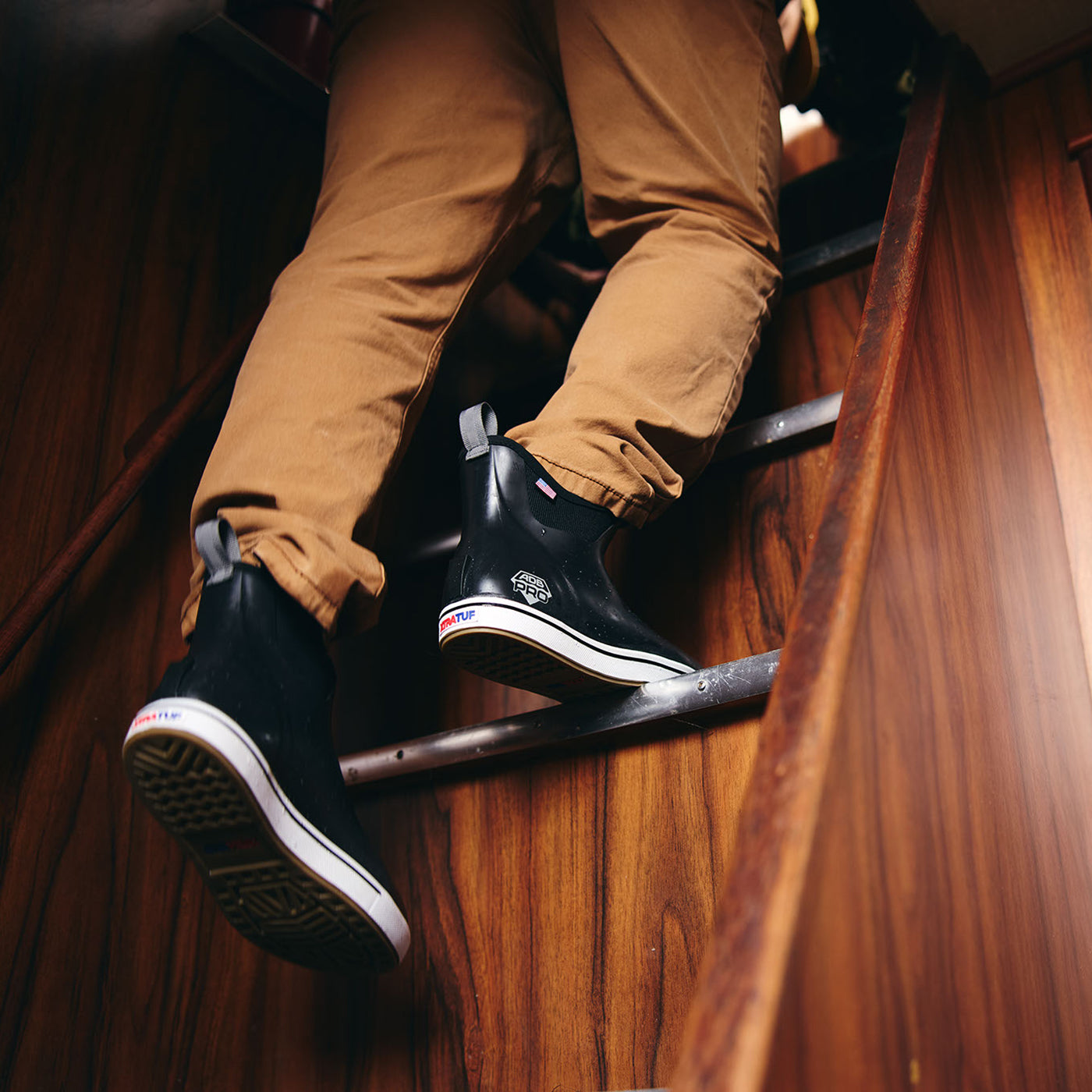 Person wearing black shoes with white soles on a wooden staircase