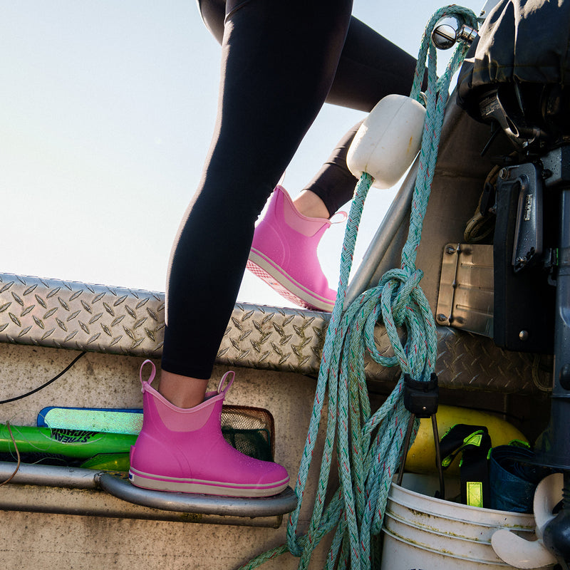 Person wearing pink boots and black leggings on a boat, with a focus on the boots.