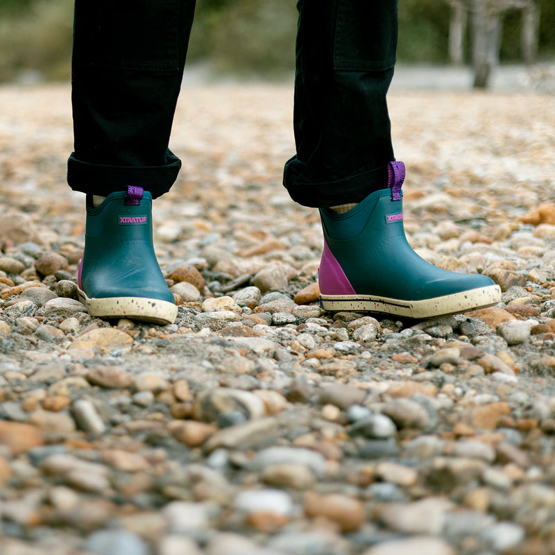 Person wearing green and purple boots on a rocky ground