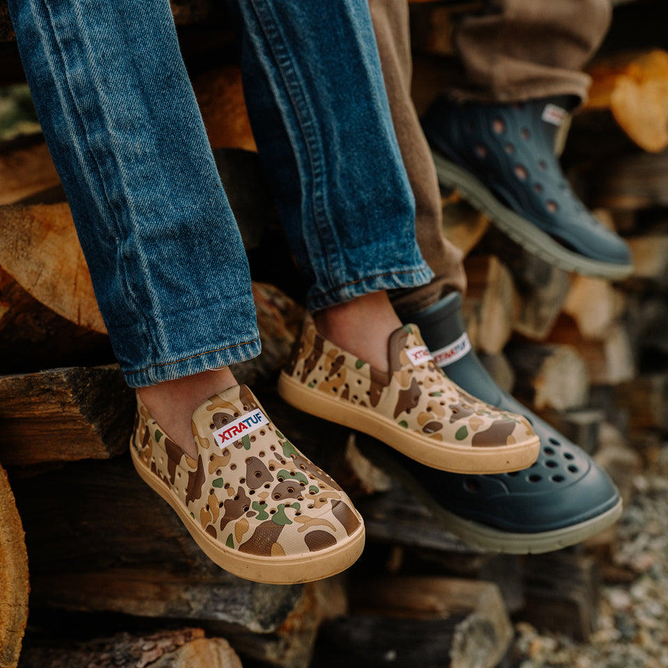 Children's feet wearing patterned shoes on a pile of wood.