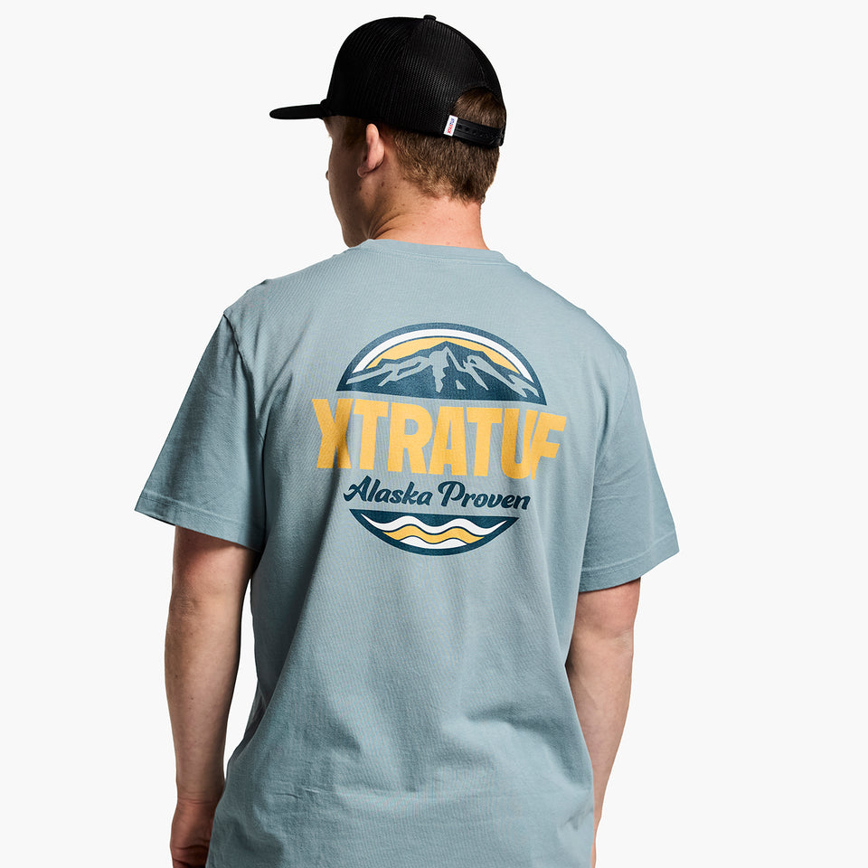 Person wearing a gray t-shirt with 'XTRATUF' logo and text on the back, white background