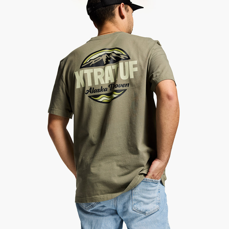 Person wearing a green t-shirt with 'XTRATUF' branding on the back, standing against a white background.