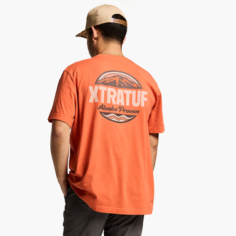 Person wearing an orange t-shirt with 'XTRATUF' branding on the back, standing against a white background.