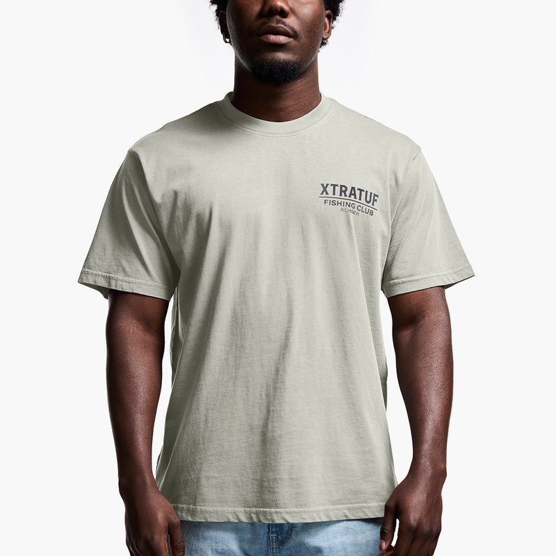 Man wearing a light gray t-shirt with 'Xtratuf Fishing Club' logo on a white background